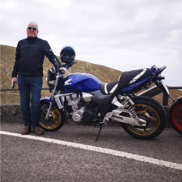Experienced 70-year-old motorcyclist riding a Honda CB1300 stopped on a scenic road during a motorcycle tour in Betancuria, Fuerteventura.