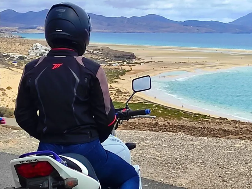 Female motorcyclist with a Honda CB1300 enjoying a scenic stop at Sotavento Beach in southern Fuerteventura during a motorcycle tour.