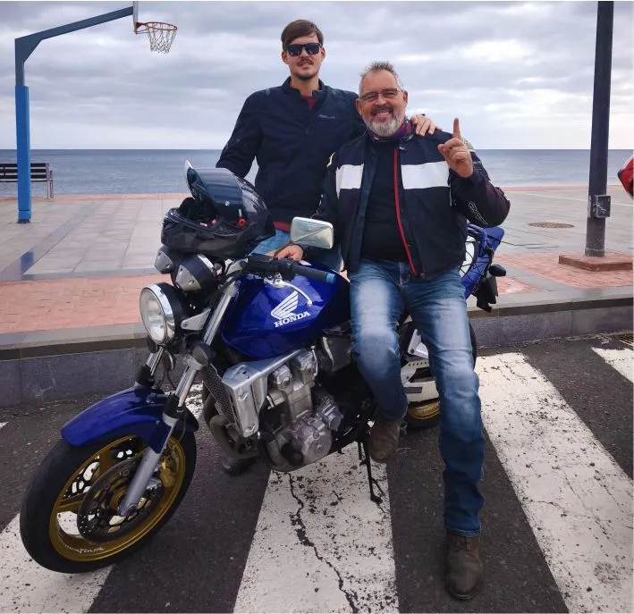 Javier, experienced motorcycle tour guide in the Canary Islands, standing on Avenida near the beach in Tarajalejo, Fuerteventura.