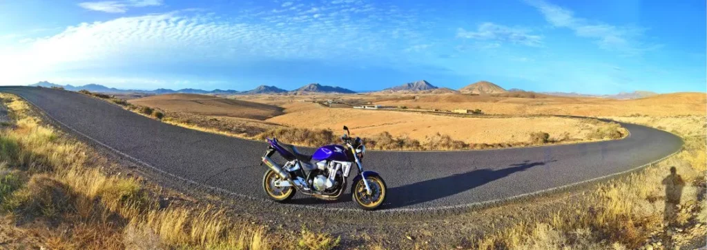 Honda CB1300 riding on a secondary road with panoramic views of Las Playitas and Gran Tarajal on a sunny day in Fuerteventura during a motorcycle tour.