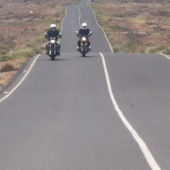Two motorcycles riding along the long desert road between Lajares and Majanicho during a scenic motorcycle tour in Fuerteventura.
