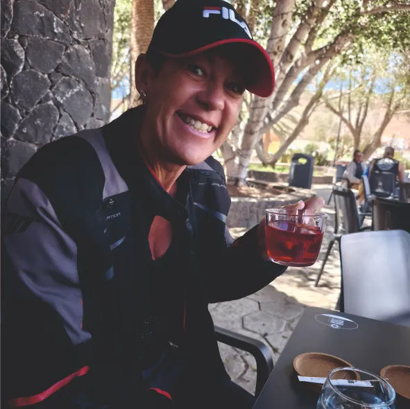 Happy client enjoying a drink during a coffee break at a café stop on a motorcycle tour in Fuerteventura.